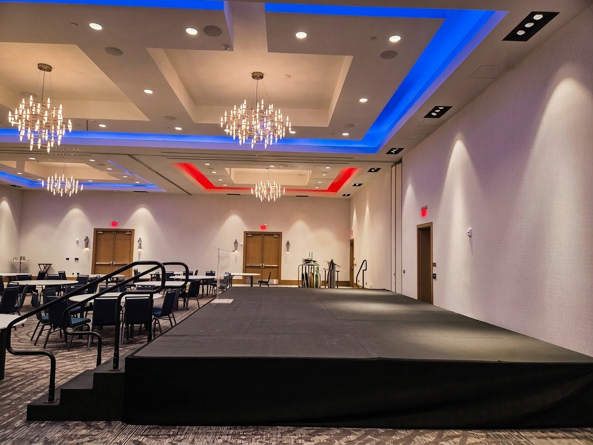 corporate stage setup inside a hotel ballroom with a clean skirted platform, podium, and stage lighting overhead