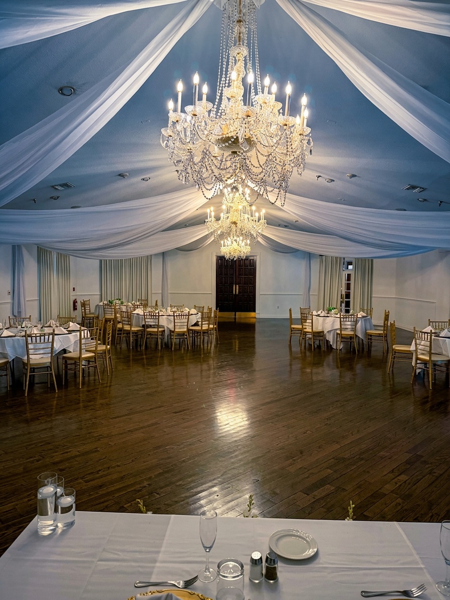white pipe and drape backdrop with twinkle lights behind a head table at an indoor wedding reception
