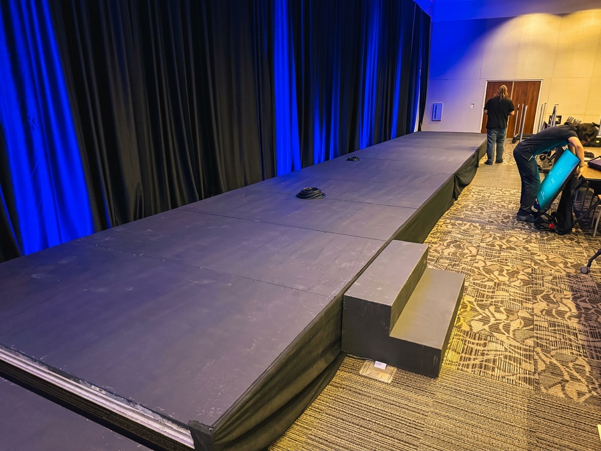 Stages Plus crew installing modular runway sections with visible deck locking system