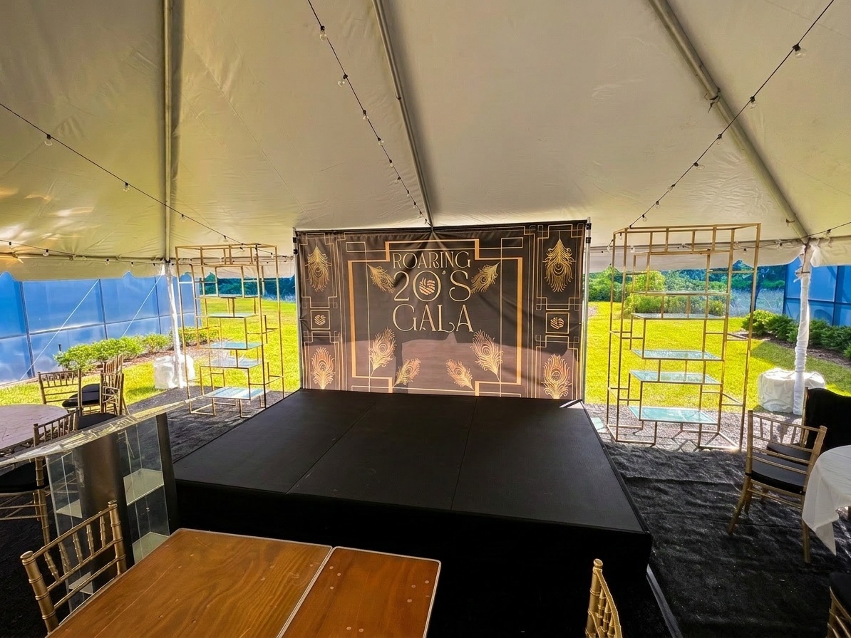 stage installed inside a large tent at an outdoor Central Florida event venue, showing tent flooring around the stage perimeter