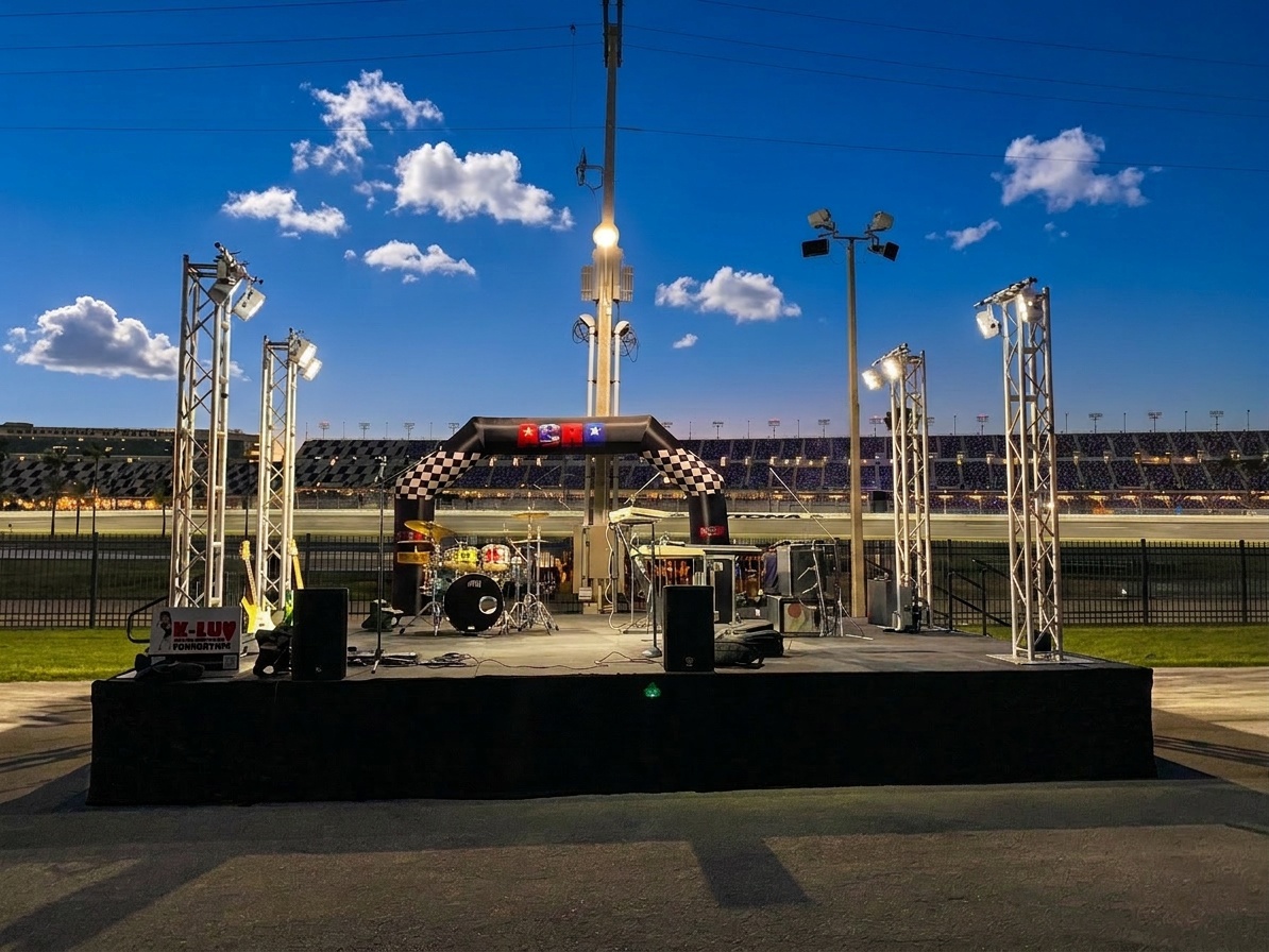 Stage installation in progress at an outdoor venue showing modular deck sections being assembled by crew